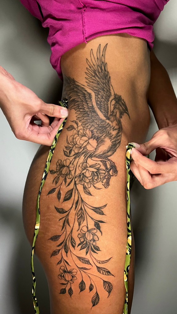 Tatuagem feminina de fênix em preto e cinza na lateral do corpo, estilo sombreado, realizada pelo tatuador no Bebeto Tattoo Studio em São Paulo.