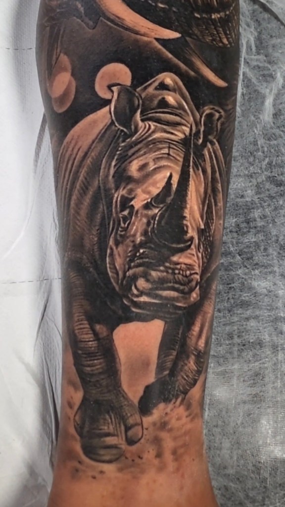 Tatuagem de rinoceronte realista em preto e cinza na canela, trabalho cicatrizado realizado pelo tatuador do Bebeto Tattoo Studio em São Paulo.